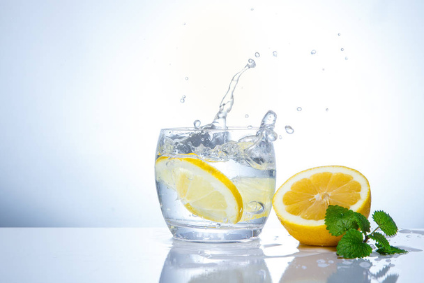 yellow lemons in a glass and splashes of water. Tasty and healthy food. Seasonal drinks - Φωτογραφία, εικόνα
