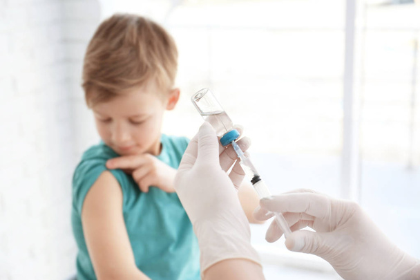 Doctor filling syringe with medicine and child on background. Vaccination day - Valokuva, kuva