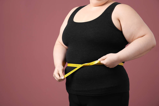 Overweight woman with measuring tape on color background - Φωτογραφία, εικόνα