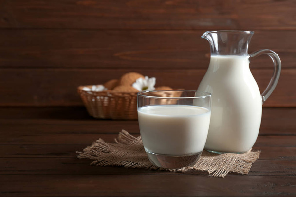 Glass and jug with milk on wooden table - Foto, immagini