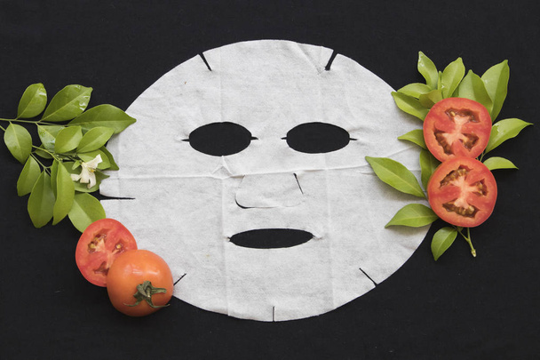 przyrodnicza arkusz opieki zdrowotnej maska dla skóry twarzy rozjaśniający z pomidorów na czarnym tle - Zdjęcie, obraz