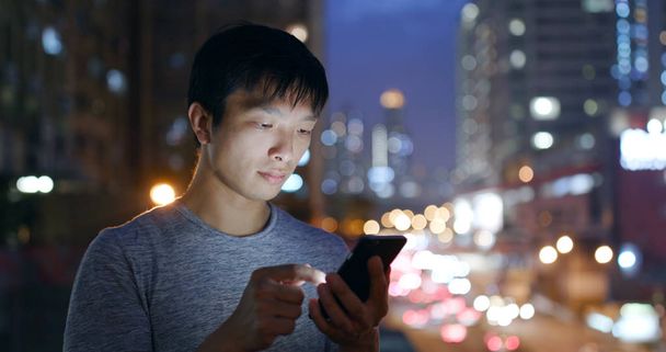 Ασιατικό άτομο χρησιμοποιώντας το κινητό τηλέφωνο στην πόλη τη νύχτα  - Φωτογραφία, εικόνα
