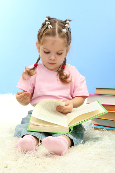 mignonne petite fille avec des livres colorés, sur fond bleu
 - Photo, image