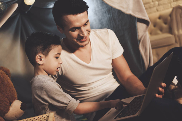 Vader en zoon kijken naar film op laptop op de Bank thuis - Foto, afbeelding