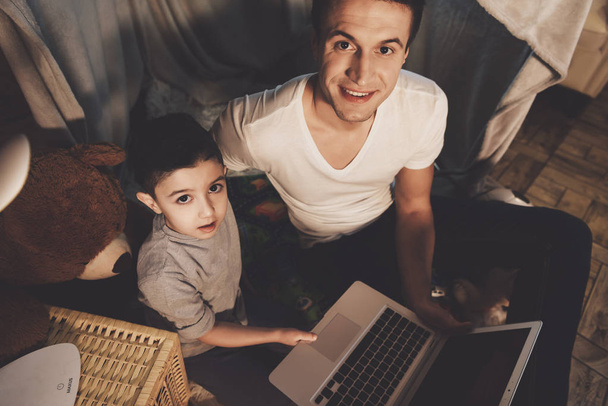 Vader en zoon kijken naar film op laptop op de Bank thuis - Foto, afbeelding