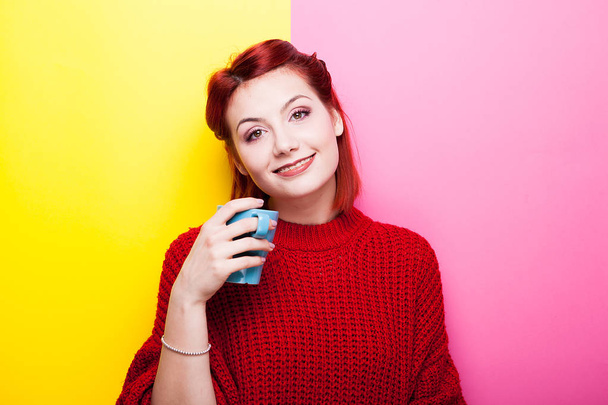 Happy woman with a cup of tea in hands looking at the camera - Фото, изображение