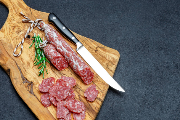 Dried organic salami sausage on wooden cutting board - Фото, изображение