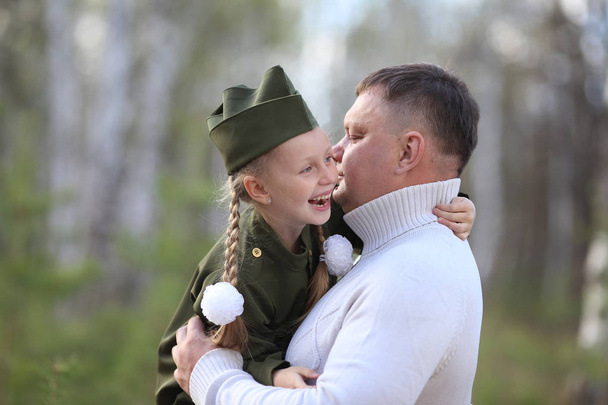 Father holding his happy daughter in uniform on the Victory Day - Фото, изображение