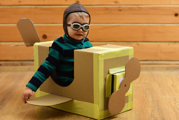 Kid, pilot school, innovation. Pilot travel, airdrome, imagination. Little boy child play in cardboard plane, childhood. Dream, career, adventure, education. Air mail delivery, aircraft construction. - Foto, afbeelding