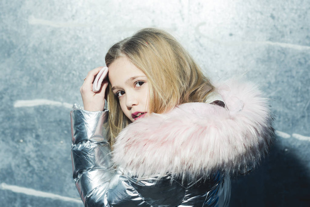 Child in winter coat with fur hood, fashion. Child fashion, trend and style concept - 写真・画像