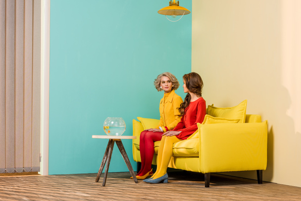 kobieta siedzi na kanapie żółty z ryb akwariowych na stolik w kolorowy apartament, koncepcja lalka domu w stylu retro - Zdjęcie, obraz