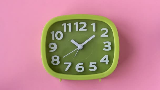 Πράσινο ρολόι με λευκά νούμερα και βέλη σε ροζ φόντο, πάροδο του χρόνου - Πλάνα, βίντεο