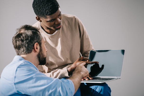 multiethnic men looking at laptop with blank screen - Fotó, kép