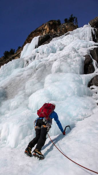 hombre escalador de hielo en una chaqueta azul en una cascada congelada gorgrous escalada en los Alpes en invierno profundo
 - Foto, Imagen