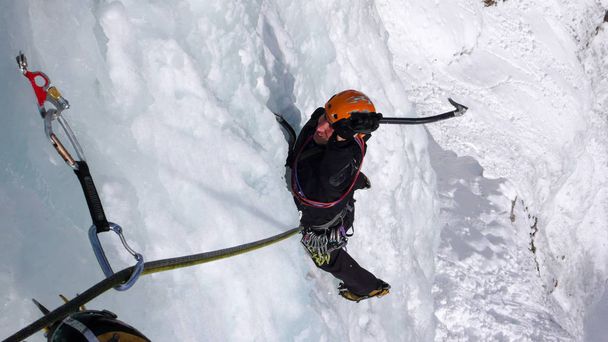 スイス アルプスの美しい冬の日に急な凍った滝に男性アイスクライマー - 写真・画像