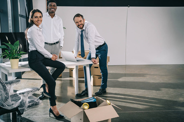 glückliche multiethnische Kollegen lächeln beim Einzug in neues Büro in die Kamera - Foto, Bild