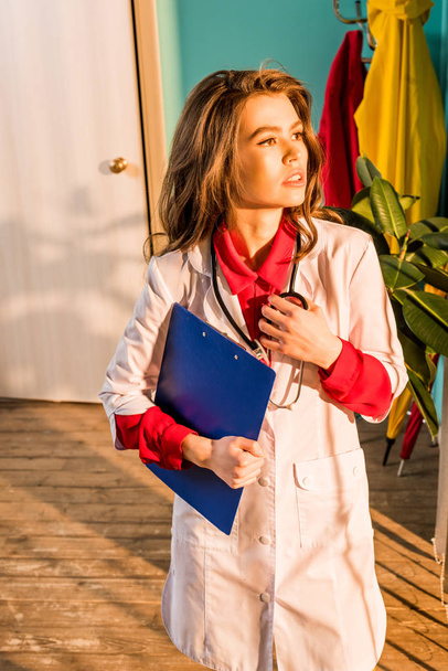 hermoso médico de estilo retro con portapapeles mirando hacia otro lado en la clínica
 - Foto, imagen