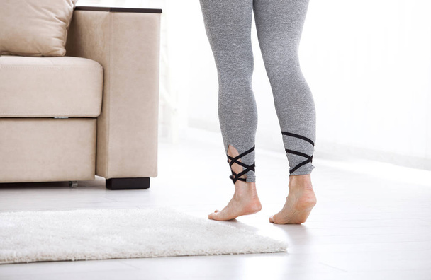 Warm floor concept. Closeup of female legs stepping by hardwood floor at home - Fotó, kép