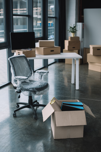 Cadeira embrulhada e caixas de papelão no escritório durante a realocação
 - Foto, Imagem
