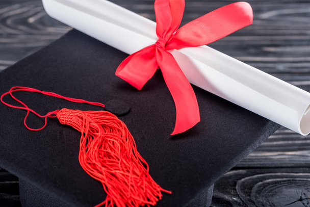 Concepto educativo con diploma y gorra de graduación en mesa de madera
 - Foto, imagen