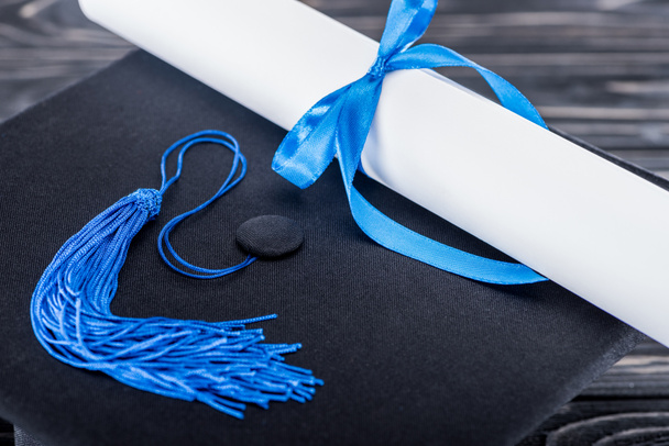 Concepto de escuela secundaria con diploma y gorra de graduación en mesa de madera
 - Foto, Imagen