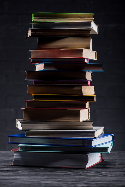 High stack of books on dark wooden background - Foto, imagen