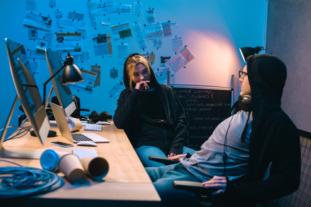 casal de jovens hackers conversando no local de trabalho no quarto escuro
 - Foto, Imagem
