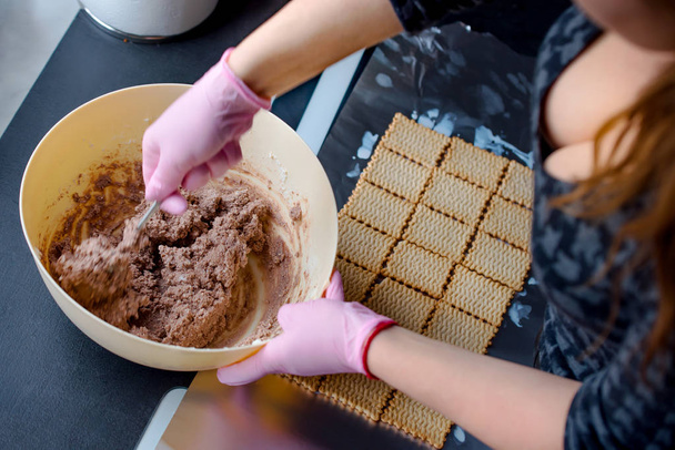 Kobieta z różowe rękawiczki przygotowania domowych ciast, shes mieszania ciasta w plastikowej miski - Zdjęcie, obraz