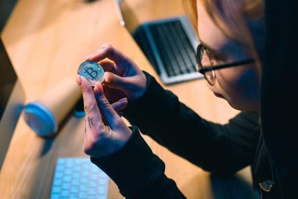 close-up shot of young female hacker holding bitcoin - 写真・画像