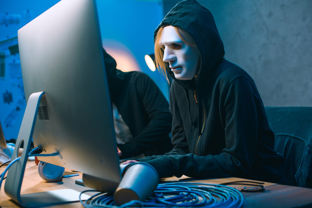 hacker en la máscara de trabajo con la computadora para desarrollar malware
 - Foto, Imagen