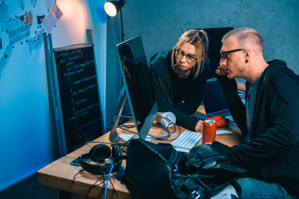 pareja pensativa de hackers mirando la pantalla de la computadora juntos en la habitación oscura
 - Foto, imagen