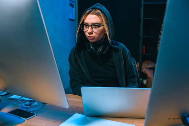 young hooded female hacker developing malware - Foto, imagen
