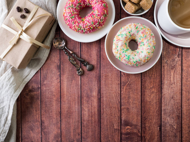 Donuts and coffee on wooden table. Top view with copy space - Фото, изображение