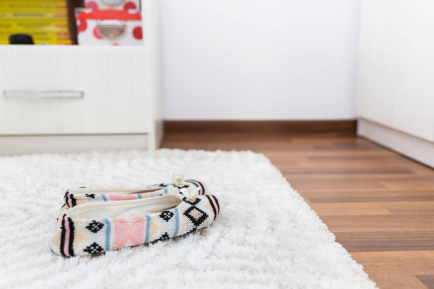 Zapatillas de casa bordadas para mujer. Zapatillas de casa bordadas manualmente para mujeres en la alfombra blanca dentro del dormitorio
. - Foto, Imagen