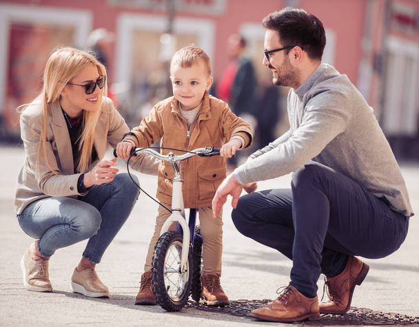 jonge familie met zoon op de fiets lopen in de stad  - Foto, afbeelding