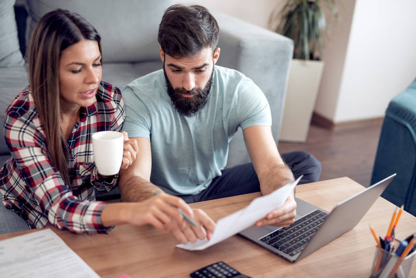 young couple checking bills with laptop at home - Photo, Image