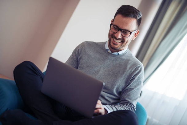 sorridente giovane uomo guardando e lavorando sul computer portatile a casa
 - Foto, immagini