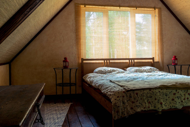 bed near a window in a room on the top floor of a wooden house,  - Фото, зображення
