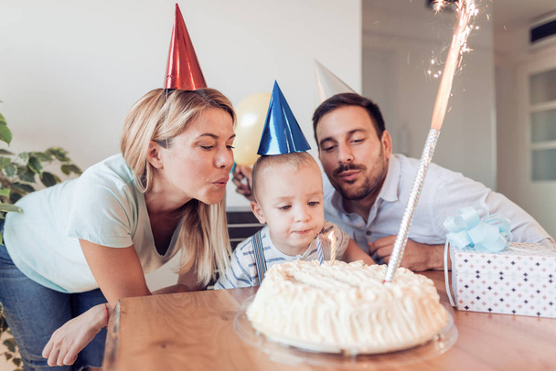  boy blows out candles on birthday cake at party - Photo, Image