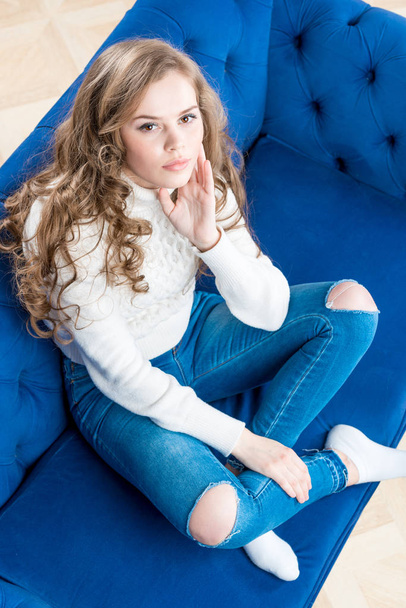 Ładna dziewczyna w ciepły sweter na kanapie w salonie Zobacz - Zdjęcie, obraz
