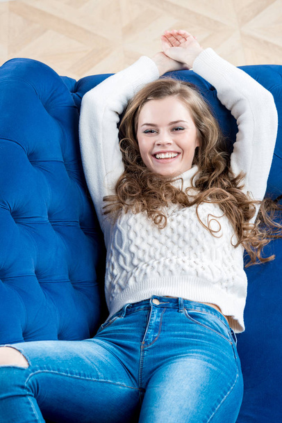 happy slim model in a sweater and jeans relaxes on the couch - Foto, Imagem
