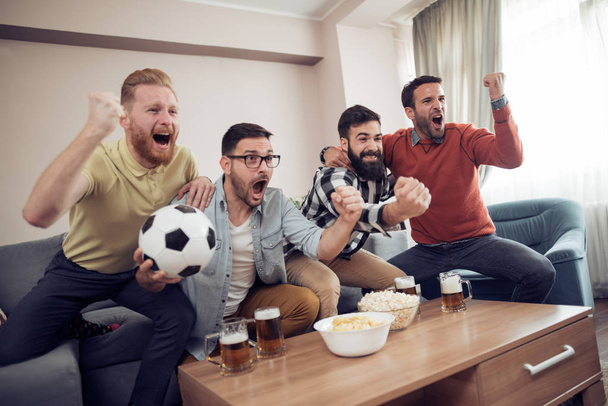 Groupe d'amis-fans de football regarder le match de football à la télévision et célébrer le but
 - Photo, image