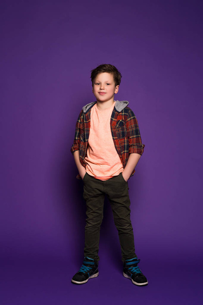 Style is more about being yourself! Full length picture of the charming child posing, while dressed in plaid shirt and trendy skinny jeans. - Foto, afbeelding
