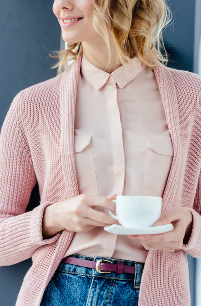 cropped shot of smiling woman in pink blouse with aromatic cup of coffee in hands - Фото, изображение