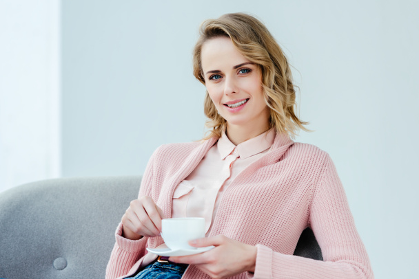 portrait of smiling woman in pink blouse with aromatic cup of coffee in hands - Photo, Image