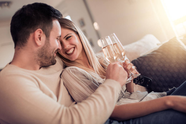 若いカップルの笑顔とワインを家で飲む - 写真・画像