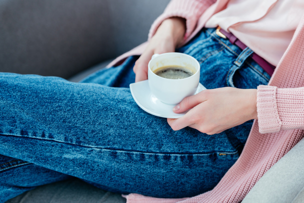 Teilansicht einer Frau in lässiger Kleidung mit einer Tasse Kaffee in der Hand - Foto, Bild