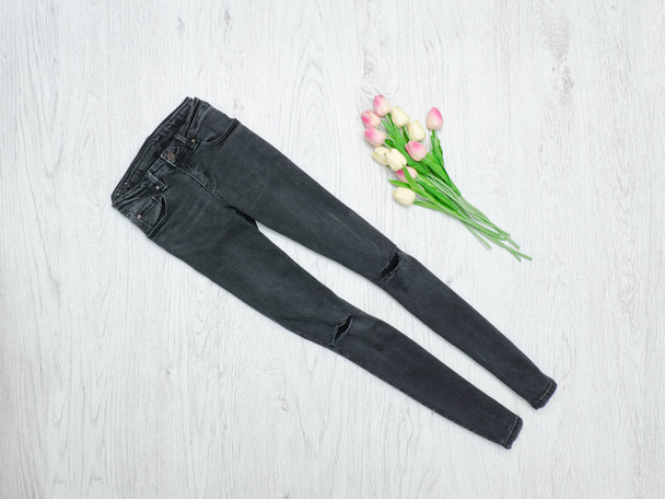 Concetto moda. Jeans strappati grigi e tulipani rosa. Fondo in legno
 - Foto, immagini