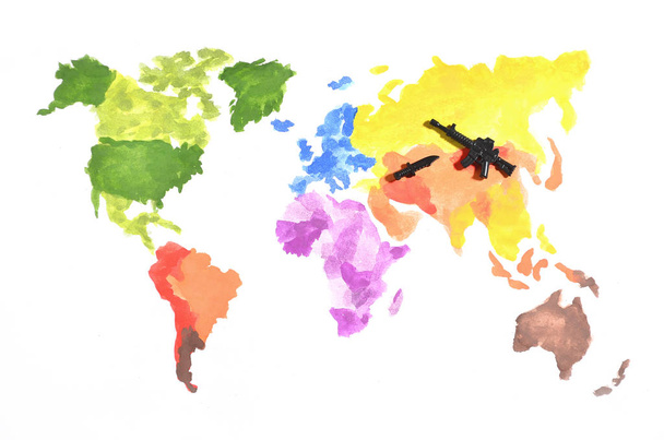 Mapa světa je vyroben s barevnými akvarel barvy na bílém podkladě s účastí černé hračku pistoli a nůž. Koncept vojenských operací v Rusku a Asii - Fotografie, Obrázek
