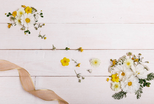 Ένα μπουκέτο από λευκά άνθη Κοσμεα ή cosmos με κορδέλα σε λευκό πίνακες. Λουλούδια στον κήπο κίτρινο φόντο Χειροποίητο ξύλινο τραπέζι. Σκηνικό με χώρο αντίγραφο. - Φωτογραφία, εικόνα